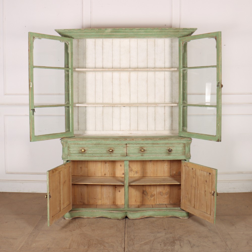 An antique West Country kitchen dresser in distressed sage green paint, featuring upper glazed doors and lower panelled cupboards. View XI