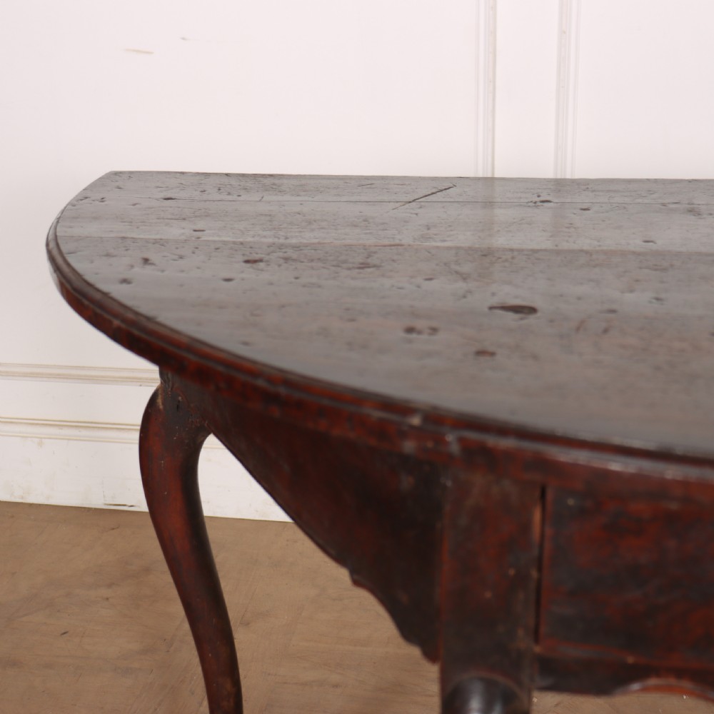 A pair of dark wood demi-lune console tables featuring semi-circular tops, single frieze drawers, and slender cabriole legs. View VII