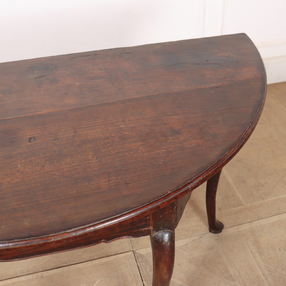 A pair of dark wood demi-lune console tables featuring semi-circular tops, single frieze drawers, and slender cabriole legs. View IX