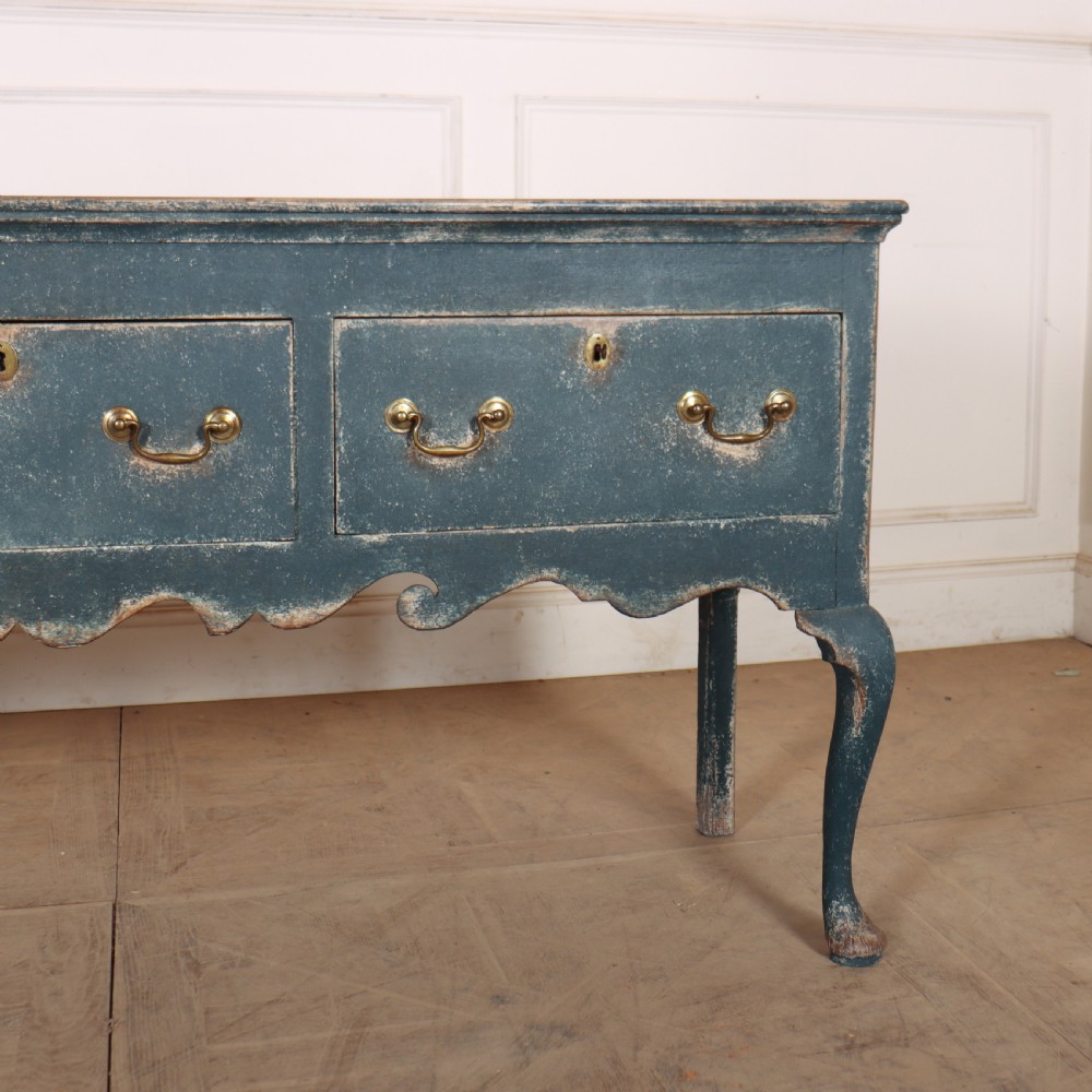 An antique blue-painted dresser base featuring three drawers with brass drop handles, a scalloped apron, and cabriole legs. View III