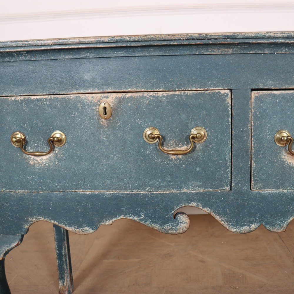An antique blue-painted dresser base featuring three drawers with brass drop handles, a scalloped apron, and cabriole legs. View VI