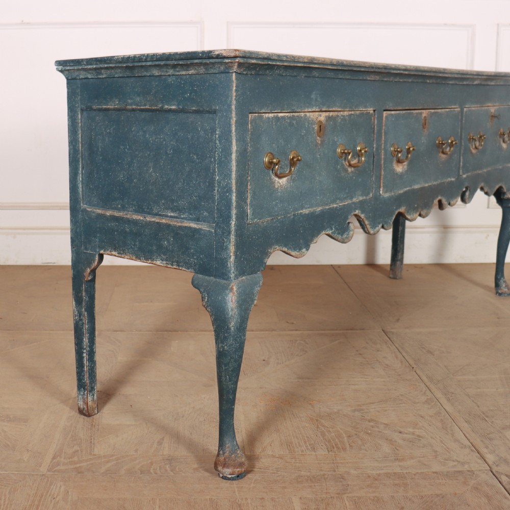 An antique blue-painted dresser base featuring three drawers with brass drop handles, a scalloped apron, and cabriole legs. View IX