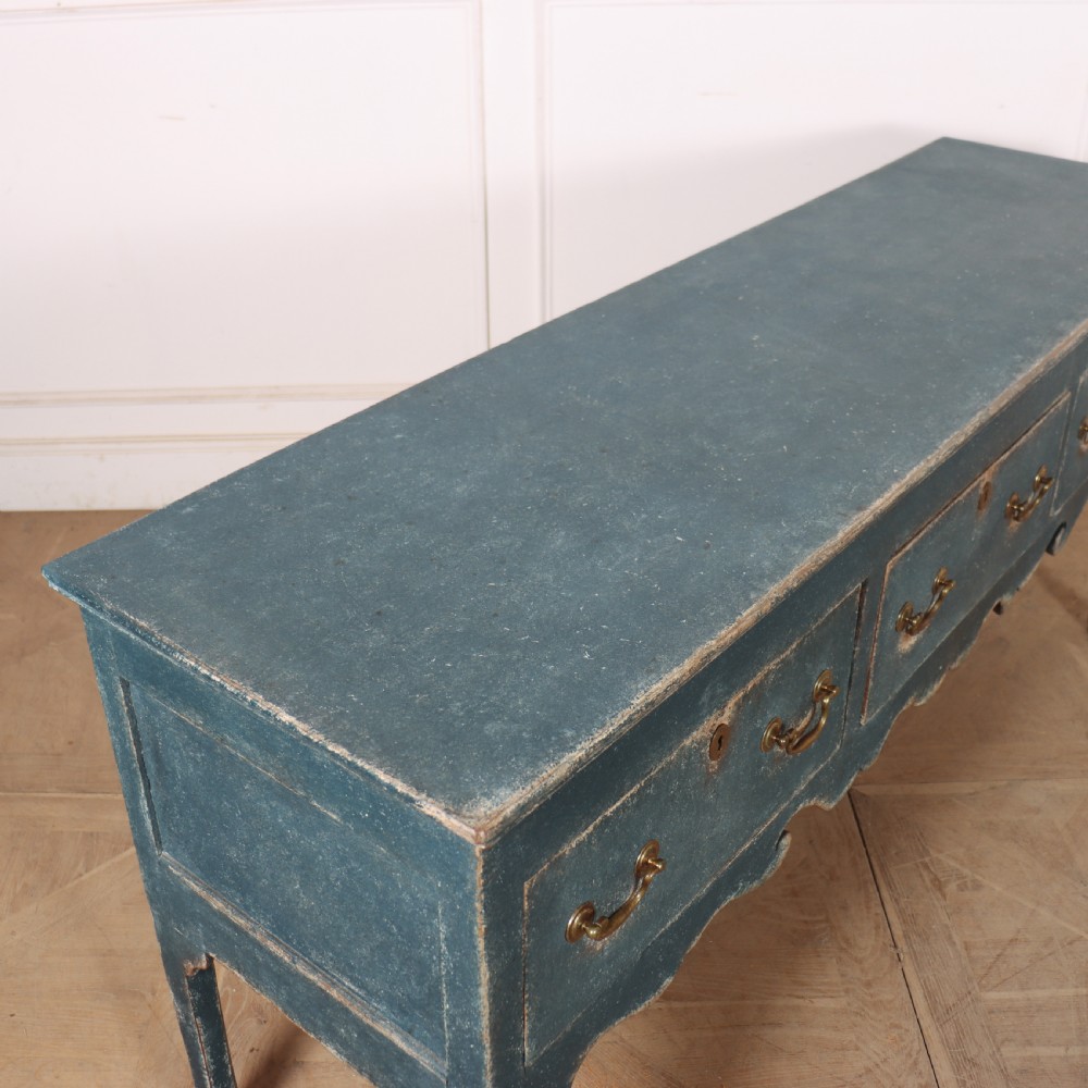An antique blue-painted dresser base featuring three drawers with brass drop handles, a scalloped apron, and cabriole legs. View XI
