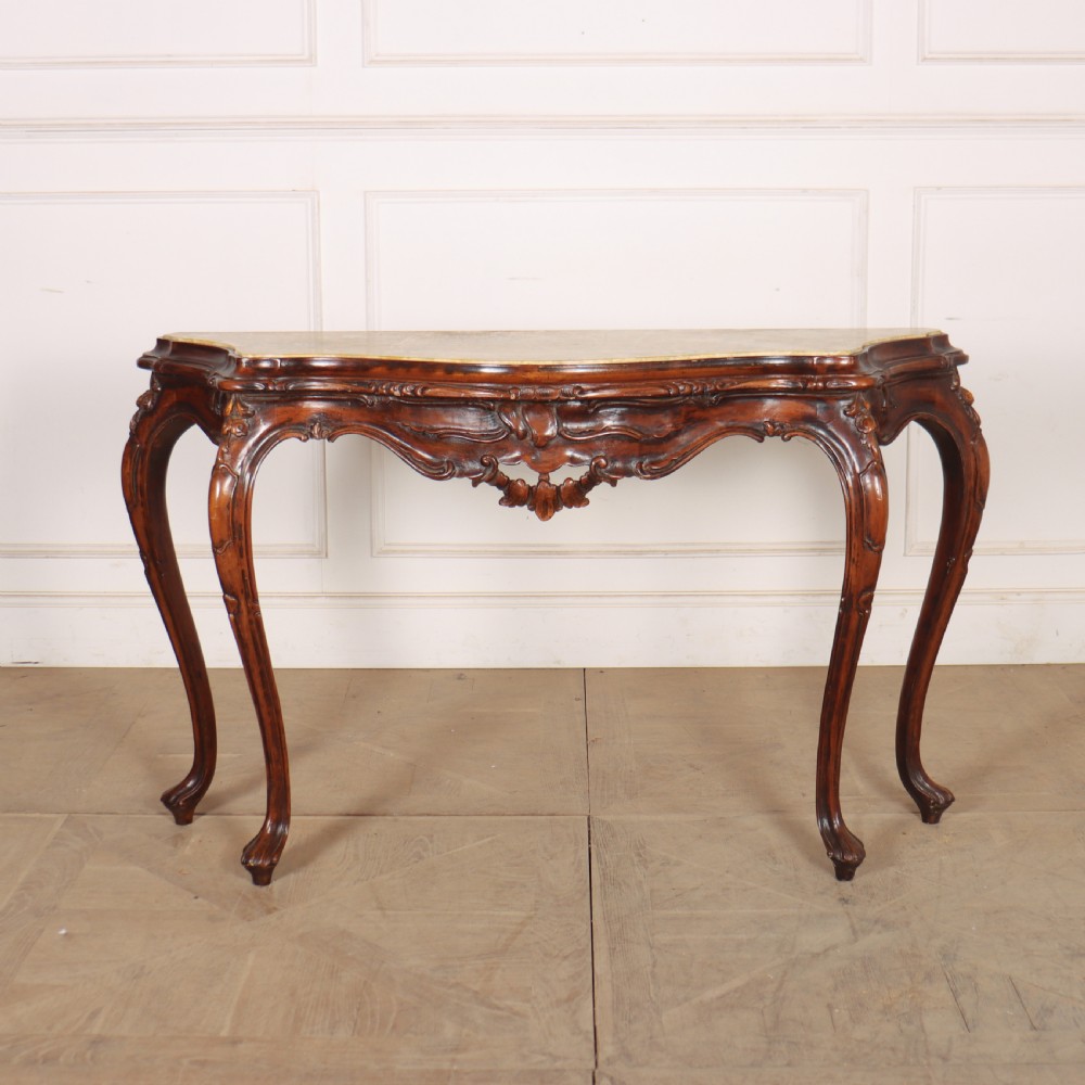 An antique 1920s Italian console table featuring a serpentine front, carved apron with scroll detailing, cabriole legs, and a marble top.
