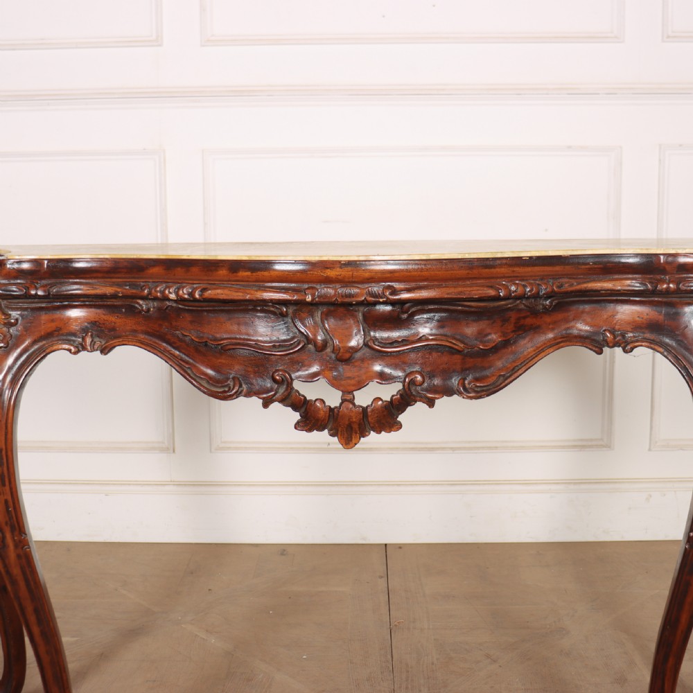 An antique 1920s Italian console table featuring a serpentine front, carved apron with scroll detailing, cabriole legs, and a marble top. View IV