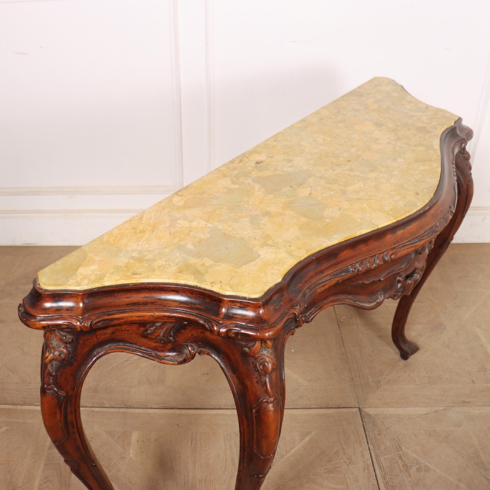 An antique 1920s Italian console table featuring a serpentine front, carved apron with scroll detailing, cabriole legs, and a marble top. View IX