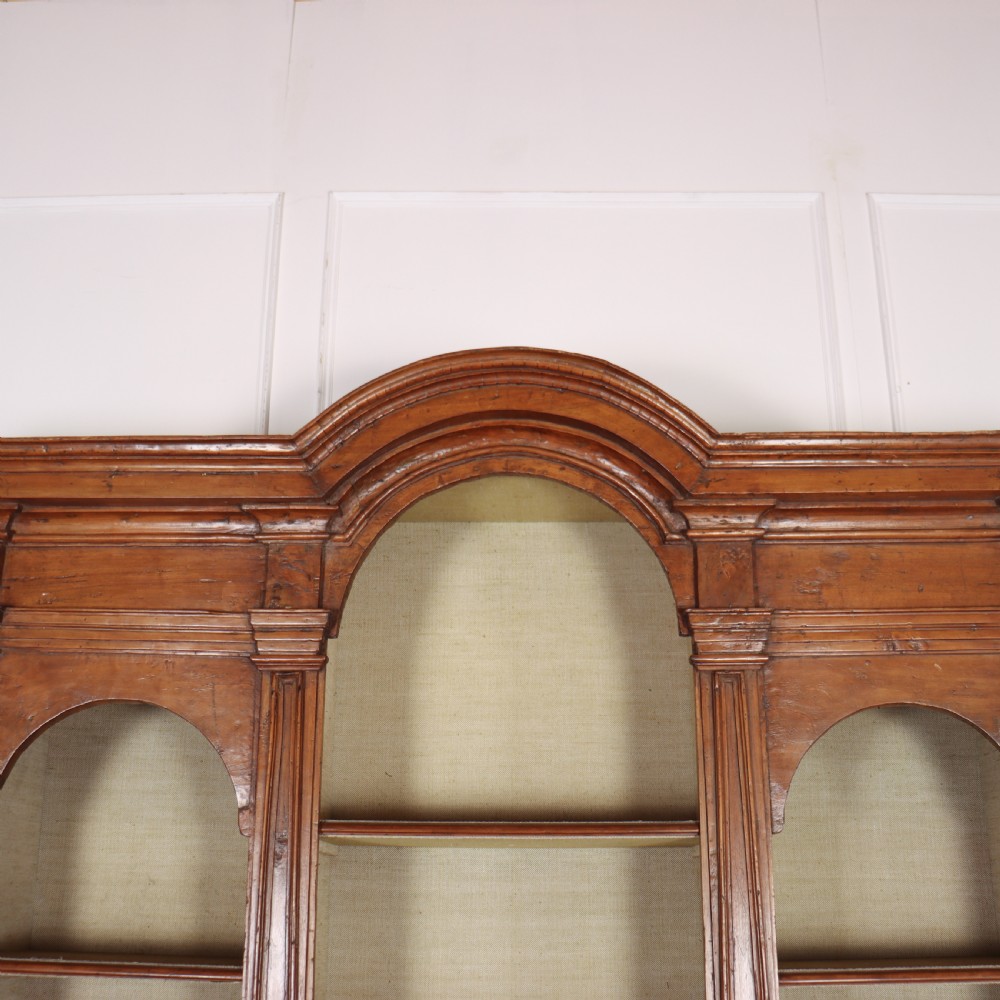 A large 1920s Italian walnut breakfront bookcase with open arched upper shelving and panelled lower cupboard doors. View III