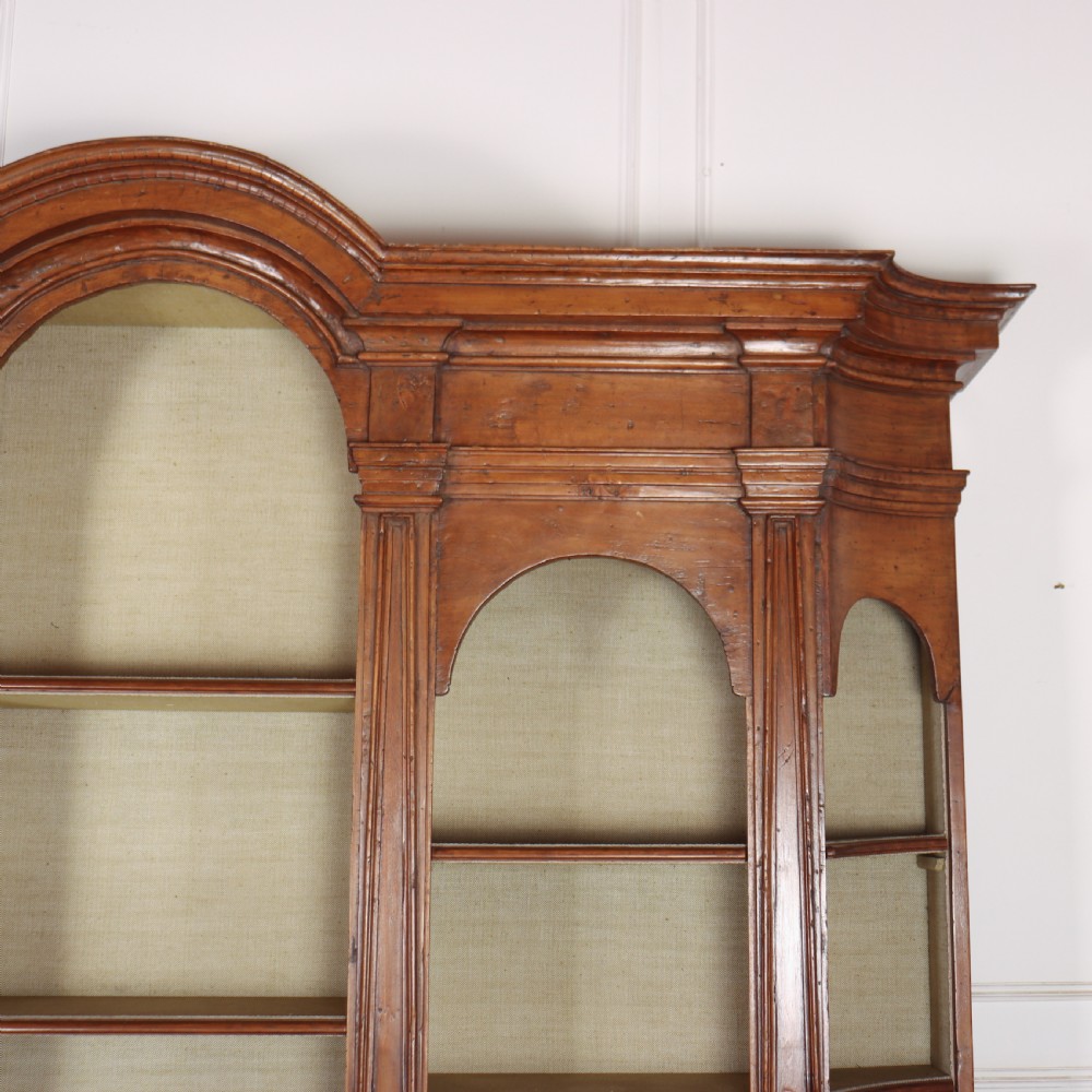 A large 1920s Italian walnut breakfront bookcase with open arched upper shelving and panelled lower cupboard doors. View V