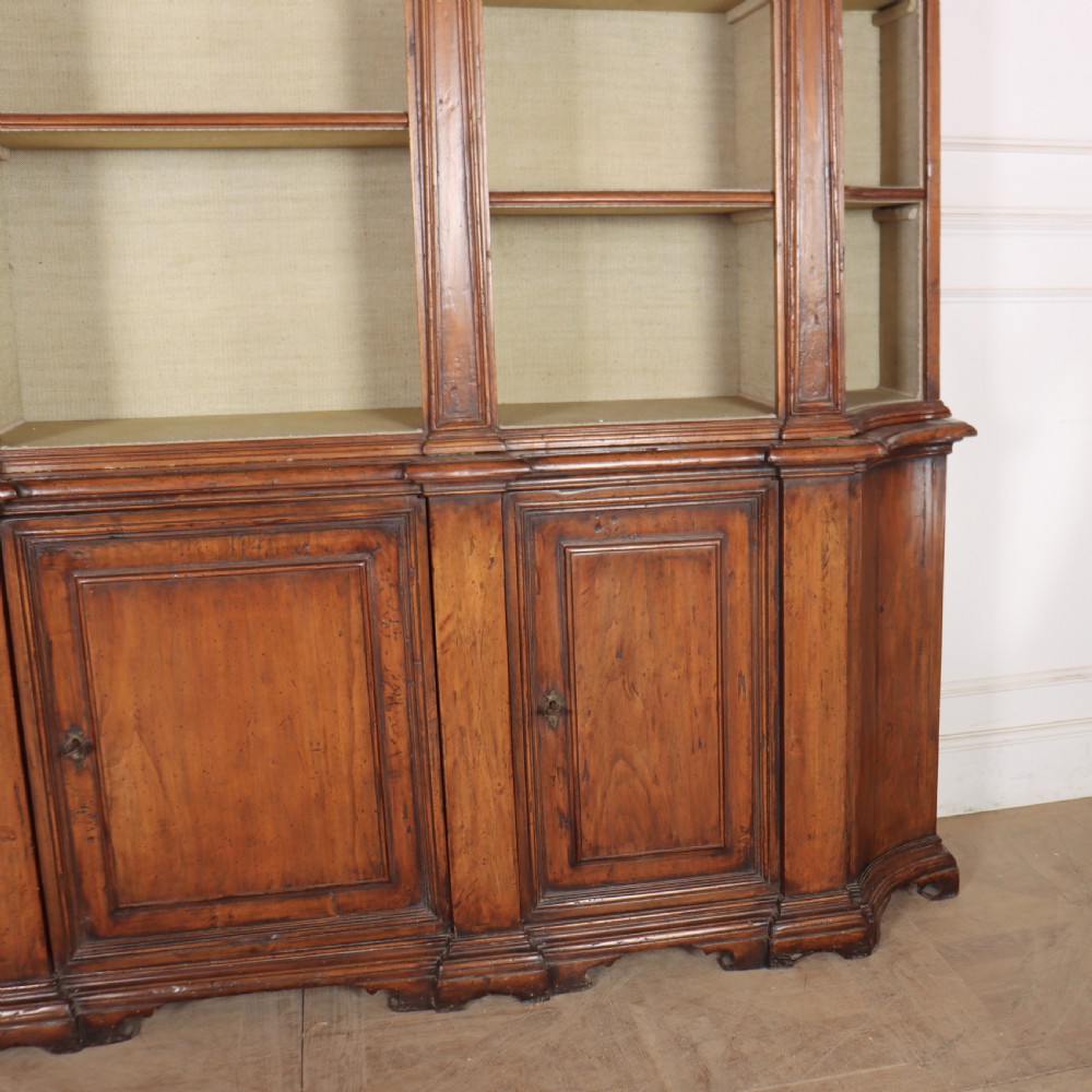 A large 1920s Italian walnut breakfront bookcase with open arched upper shelving and panelled lower cupboard doors. View VIII