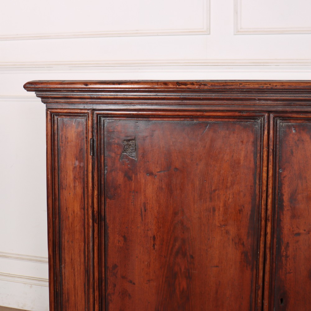 A large antique Italian dark walnut sideboard featuring four moulded rectangular panel doors and a solid plinth base. View II