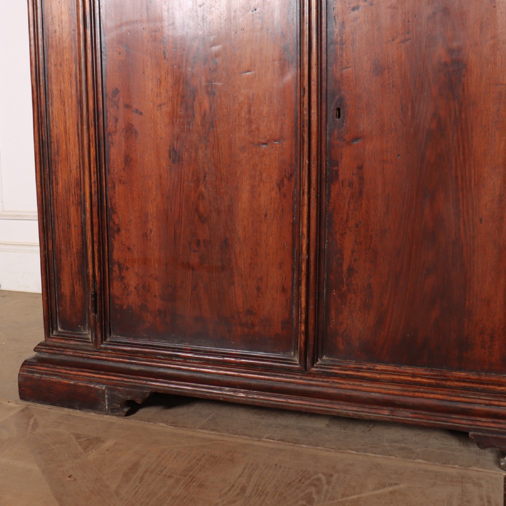 A large antique Italian dark walnut sideboard featuring four moulded rectangular panel doors and a solid plinth base. View V