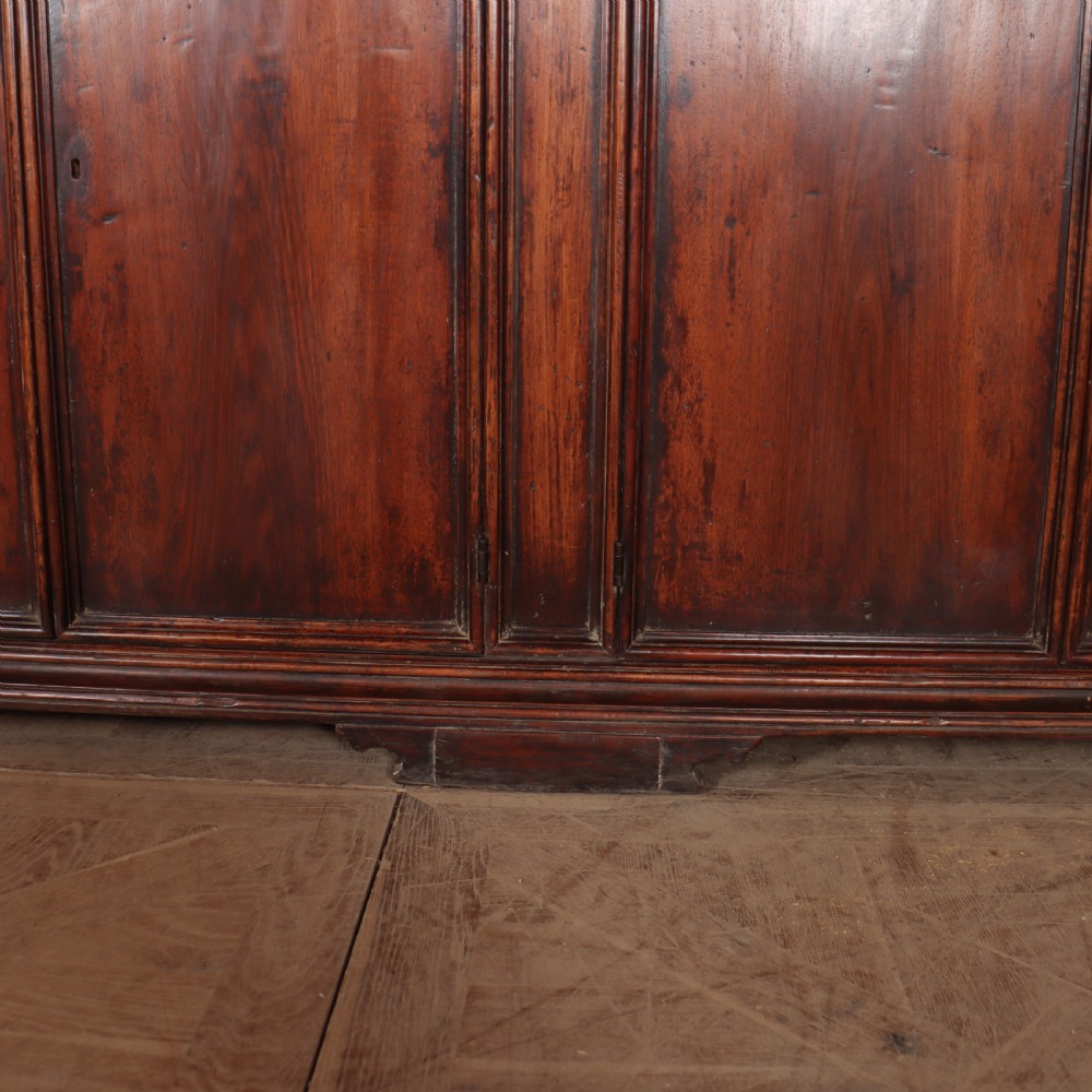 A large antique Italian dark walnut sideboard featuring four moulded rectangular panel doors and a solid plinth base. View VII