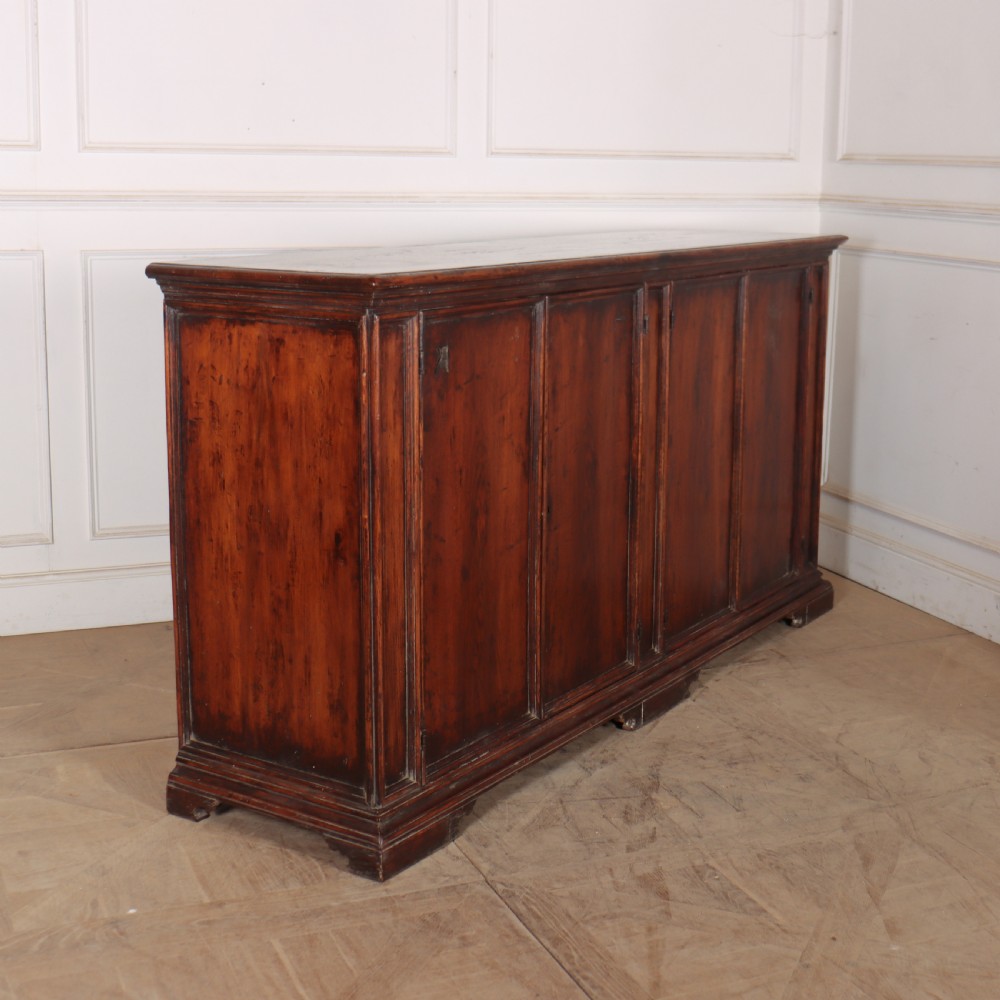 A large antique Italian dark walnut sideboard featuring four moulded rectangular panel doors and a solid plinth base. View IX
