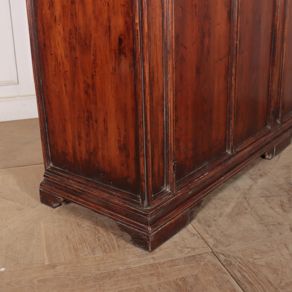 A large antique Italian dark walnut sideboard featuring four moulded rectangular panel doors and a solid plinth base. View XI