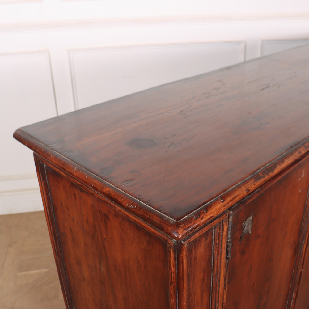 A large antique Italian dark walnut sideboard featuring four moulded rectangular panel doors and a solid plinth base. View XII