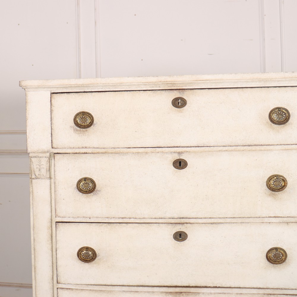 An off-white painted tallboy chest of drawers featuring six stacked drawers with round brass handles and keyhole escutcheons. View V