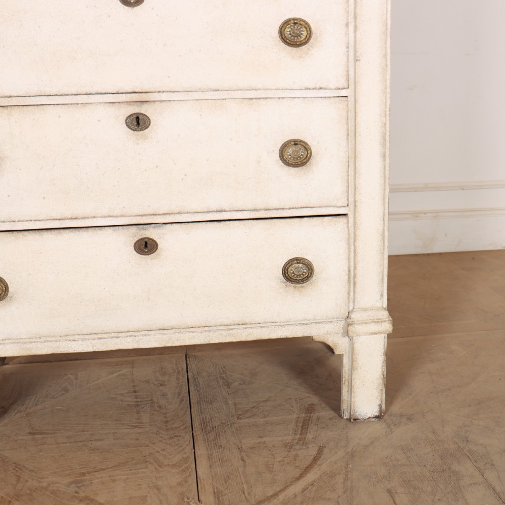 An off-white painted tallboy chest of drawers featuring six stacked drawers with round brass handles and keyhole escutcheons. View VI