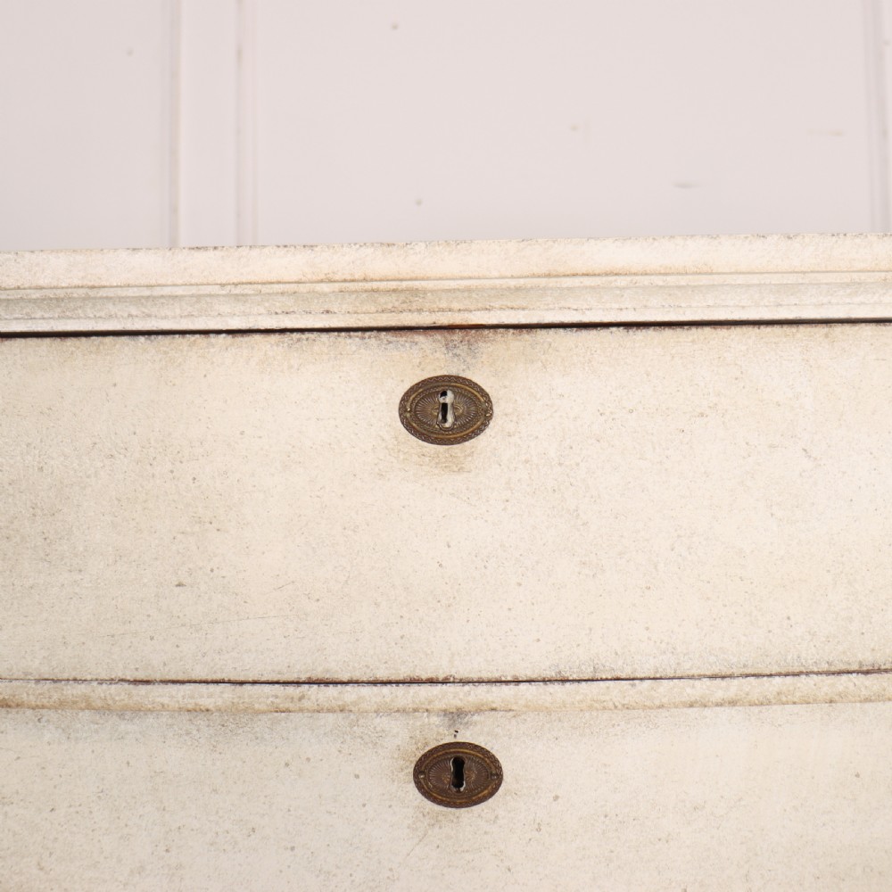 An off-white painted tallboy chest of drawers featuring six stacked drawers with round brass handles and keyhole escutcheons. View VII