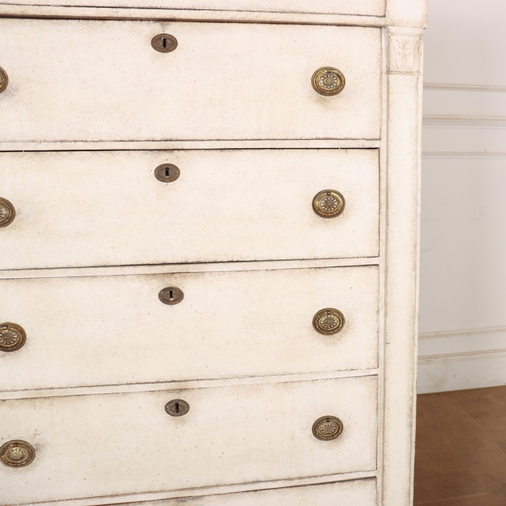 An off-white painted tallboy chest of drawers featuring six stacked drawers with round brass handles and keyhole escutcheons. View IX
