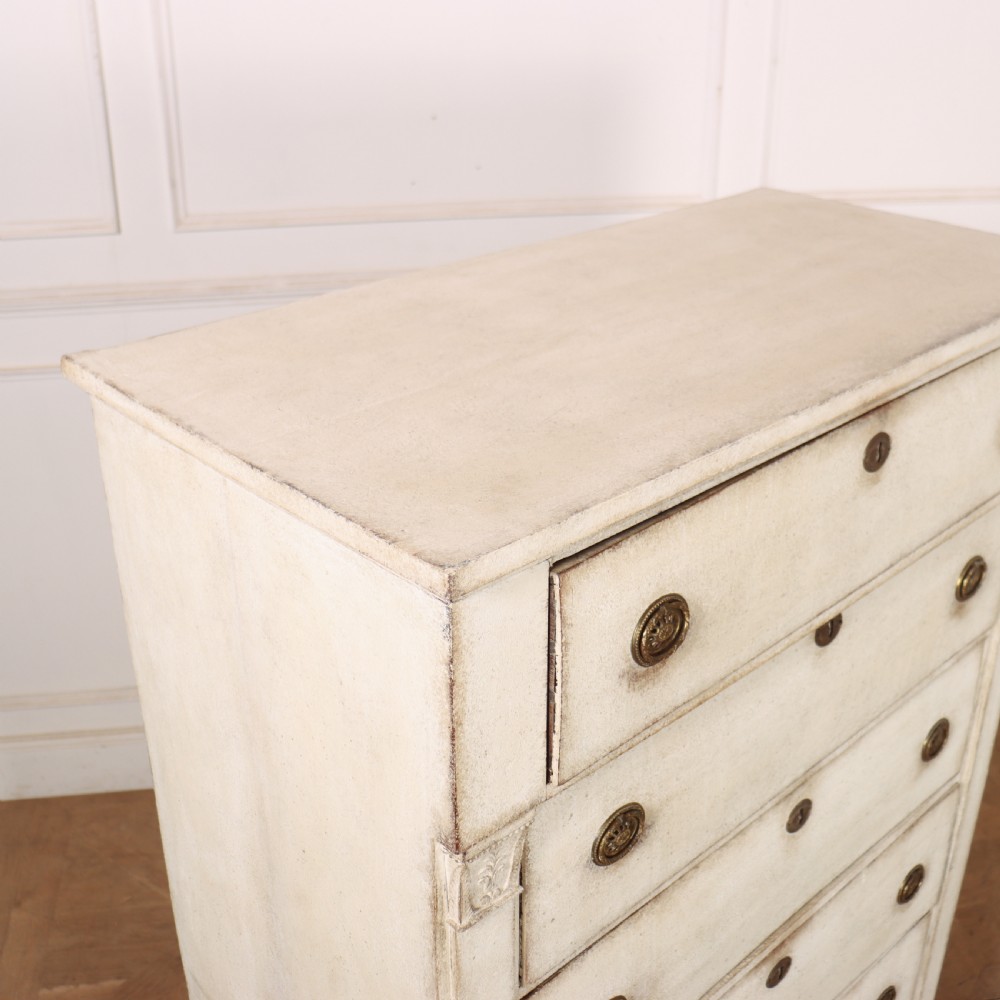 An off-white painted tallboy chest of drawers featuring six stacked drawers with round brass handles and keyhole escutcheons. View XII