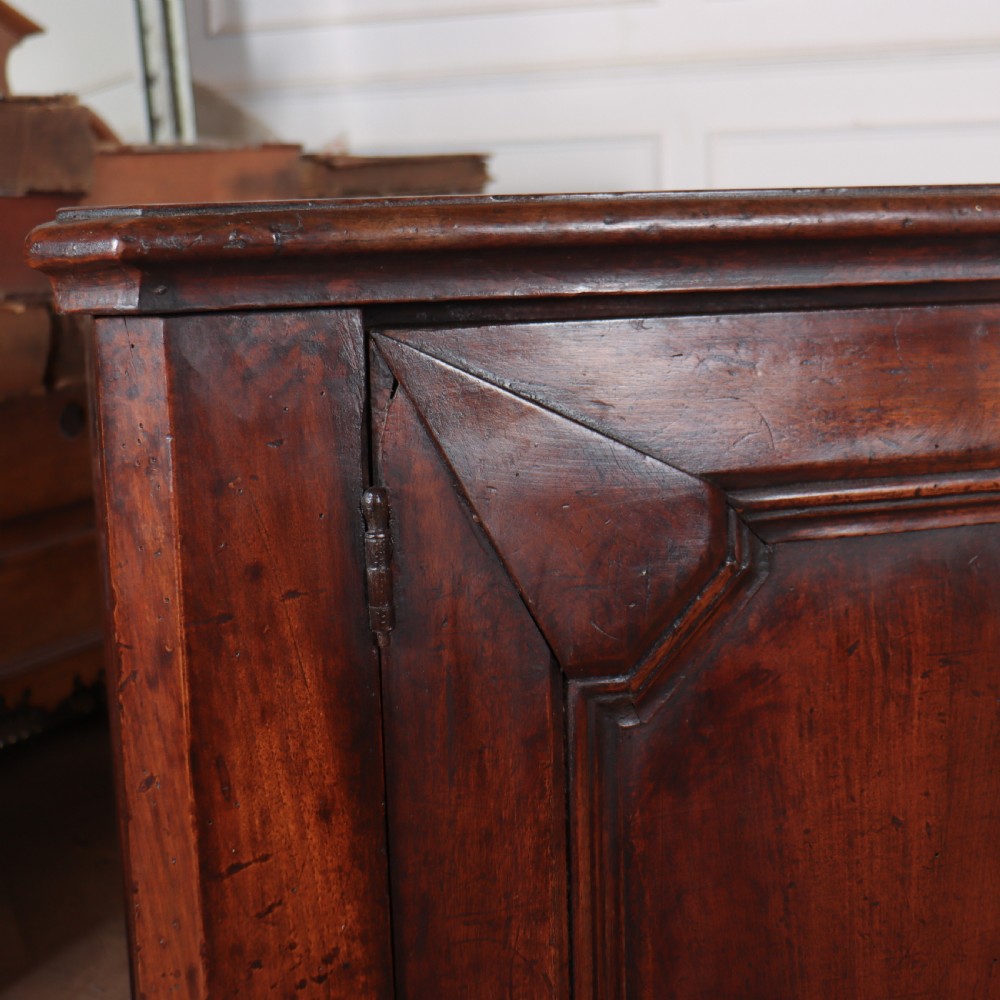 A long, monumental dark walnut Italian credenza featuring geometric moulded panel doors, a central column of drawers, and carved plinth feet. View IV