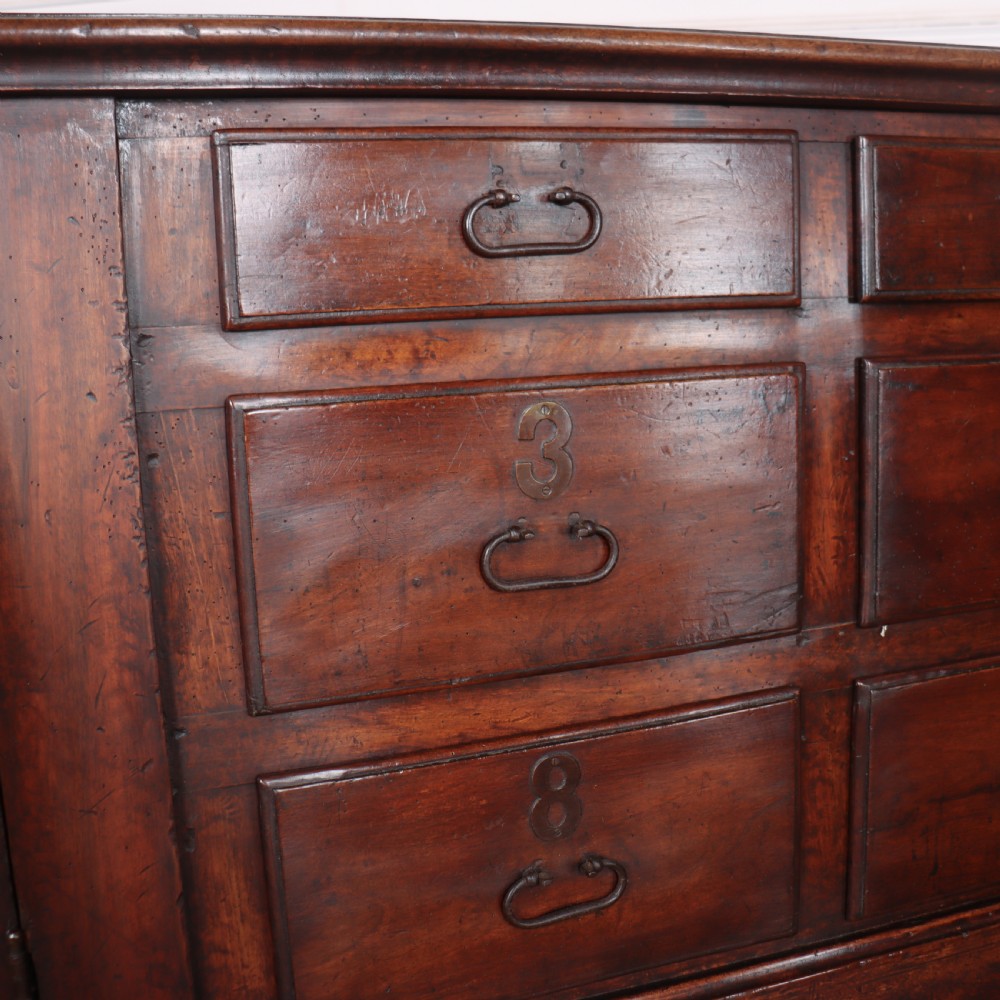 A long, monumental dark walnut Italian credenza featuring geometric moulded panel doors, a central column of drawers, and carved plinth feet. View VI