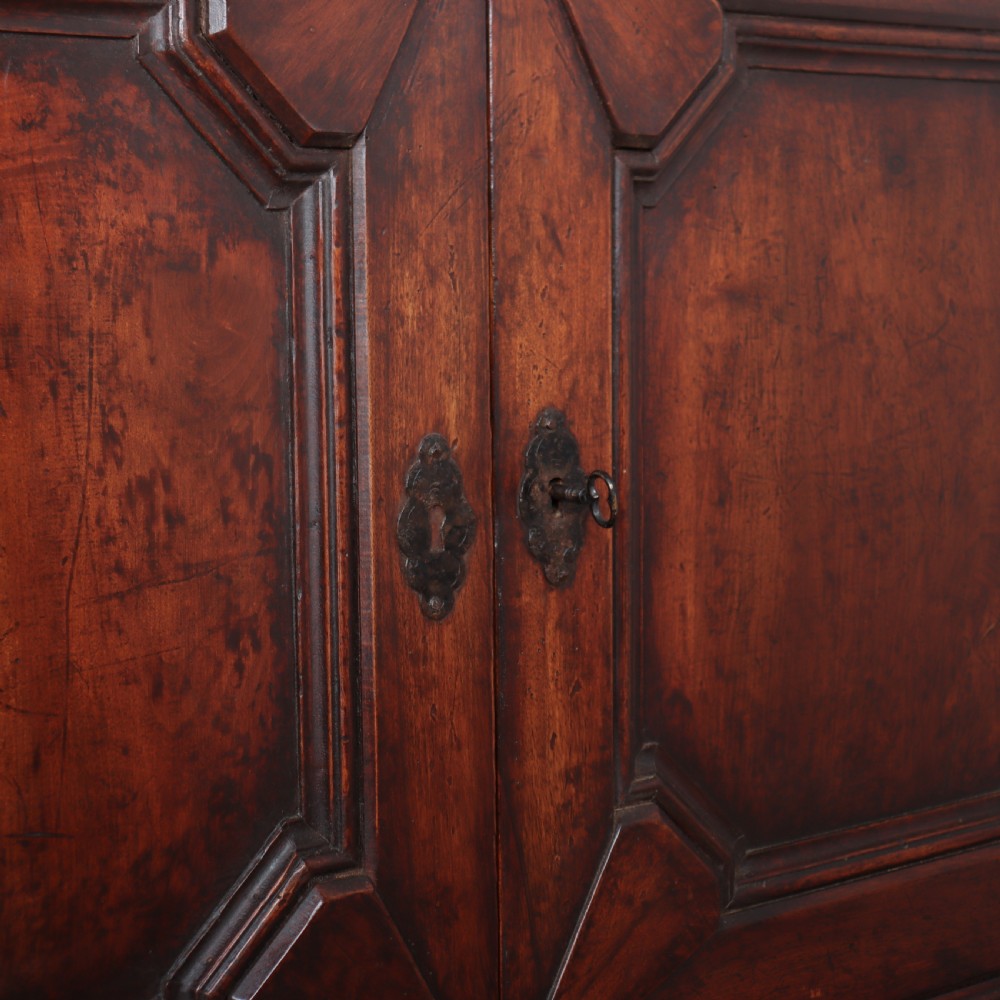 A long, monumental dark walnut Italian credenza featuring geometric moulded panel doors, a central column of drawers, and carved plinth feet. View X