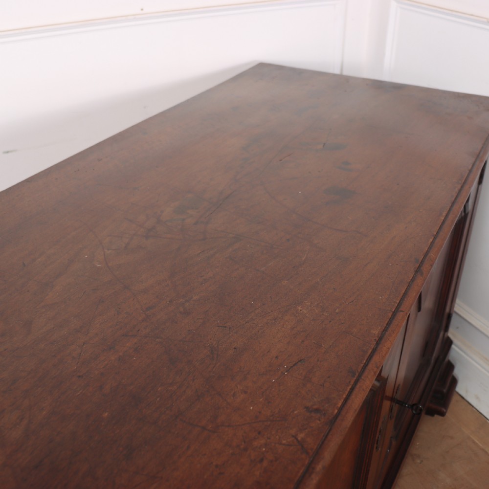 A long, monumental dark walnut Italian credenza featuring geometric moulded panel doors, a central column of drawers, and carved plinth feet. View XV