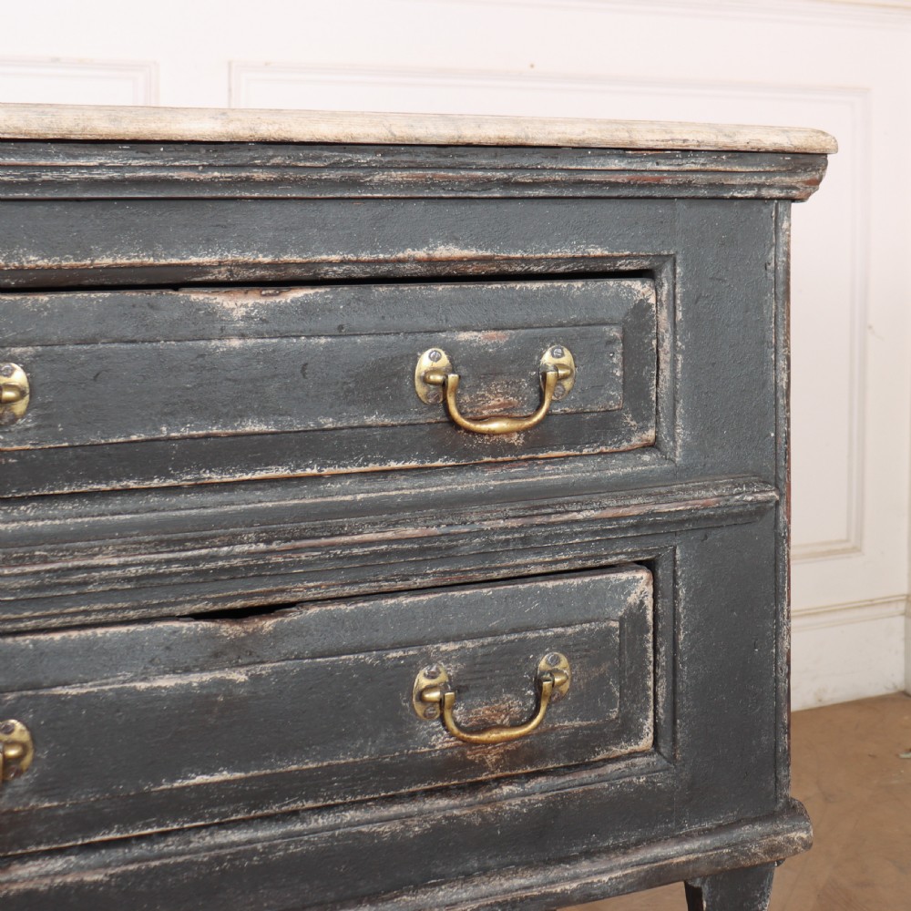 An English painted dresser base featuring a dark charcoal finish, four wide drawers with brass drop handles, shaped corner legs, and a light marble top. View V