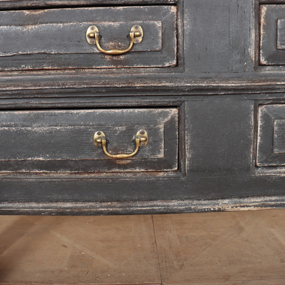 An English painted dresser base featuring a dark charcoal finish, four wide drawers with brass drop handles, shaped corner legs, and a light marble top. View VIII