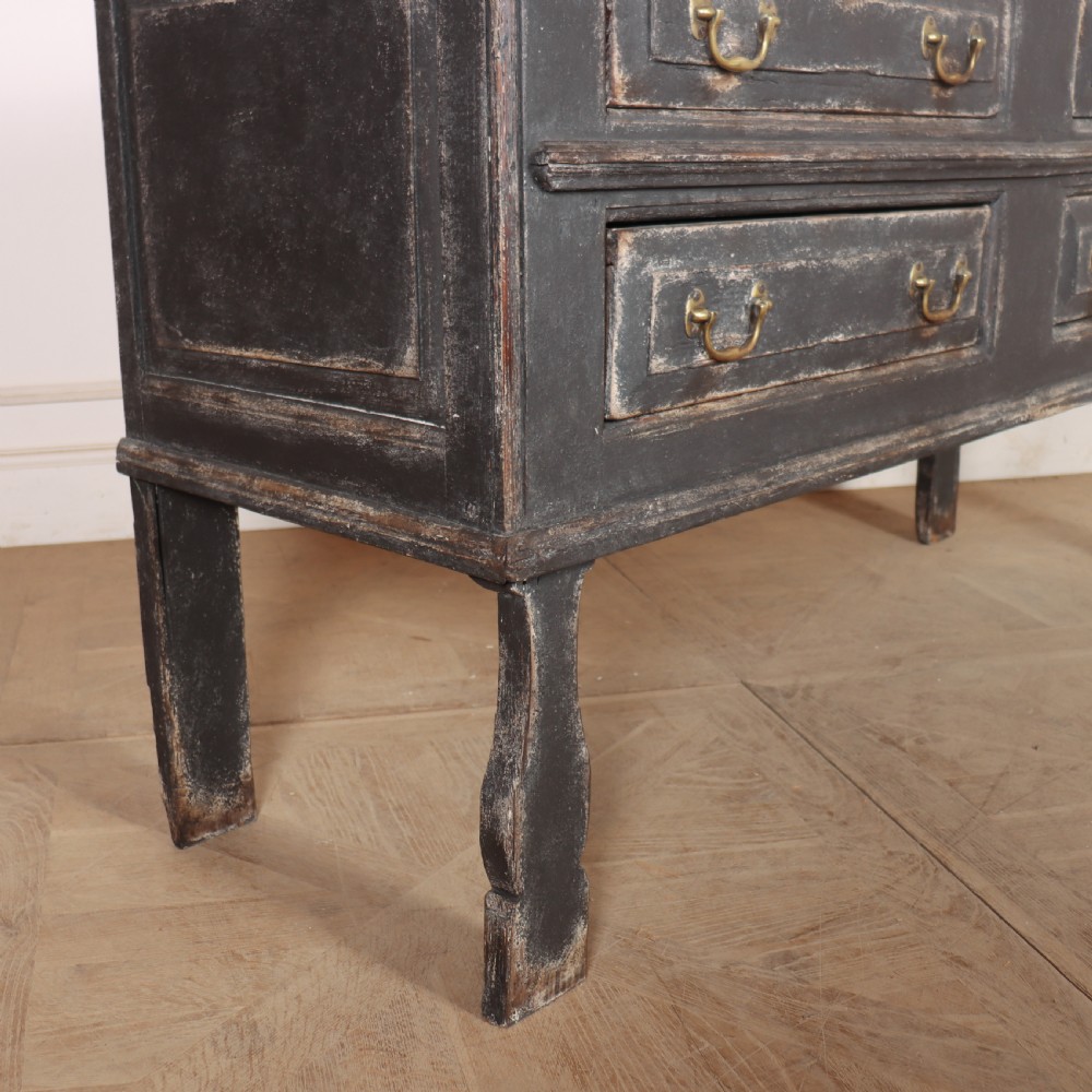 An English painted dresser base featuring a dark charcoal finish, four wide drawers with brass drop handles, shaped corner legs, and a light marble top. View XIII