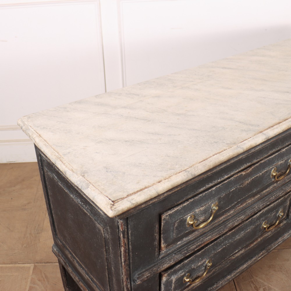 An English painted dresser base featuring a dark charcoal finish, four wide drawers with brass drop handles, shaped corner legs, and a light marble top. View XIV