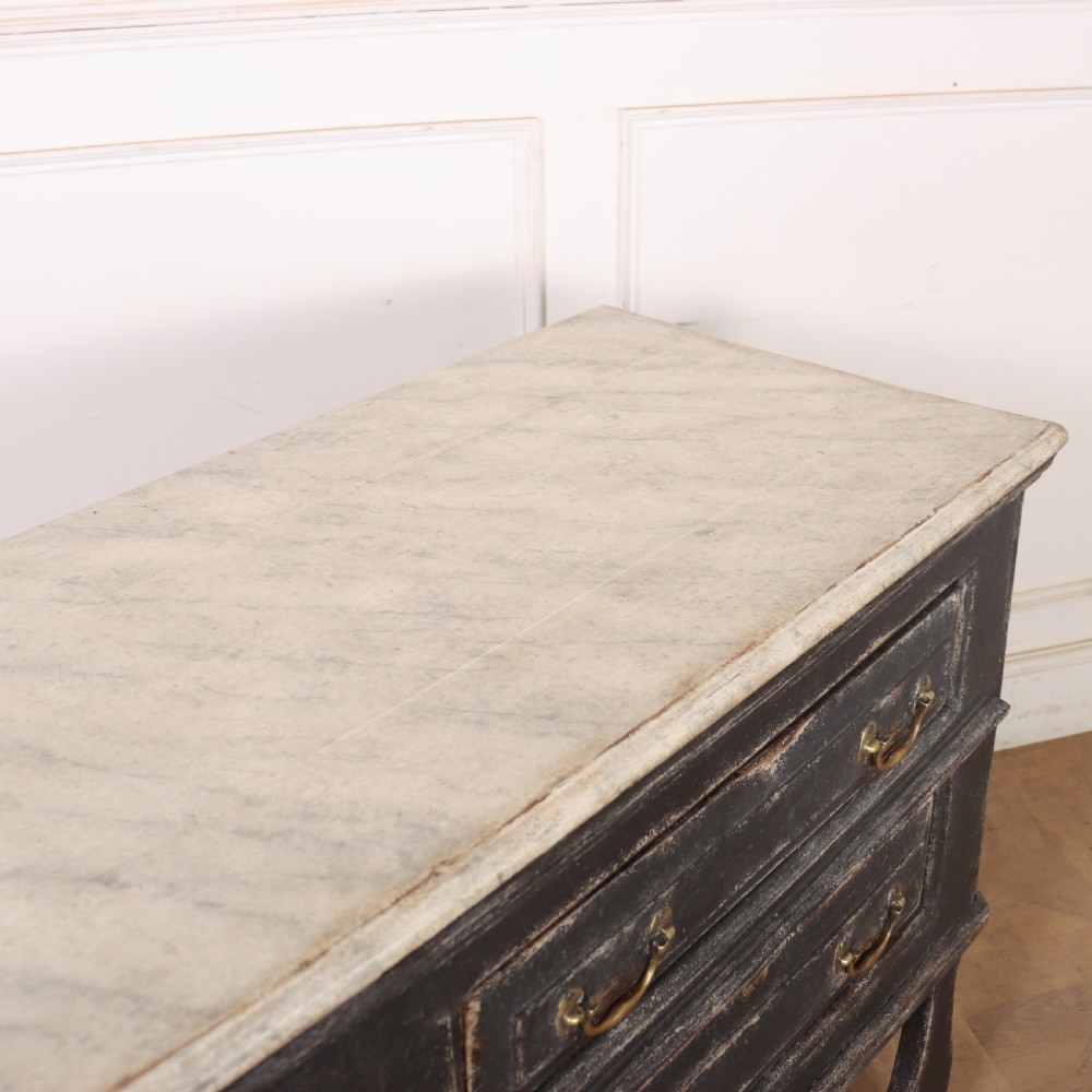 An English painted dresser base featuring a dark charcoal finish, four wide drawers with brass drop handles, shaped corner legs, and a light marble top. View XV