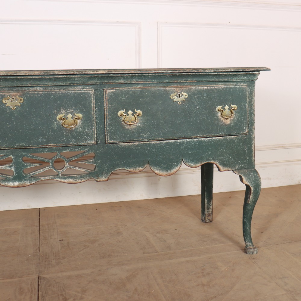 A long antique green painted dresser base featuring three drawers with brass handles, a scalloped apron with pierced fretwork, and cabriole legs. View IV