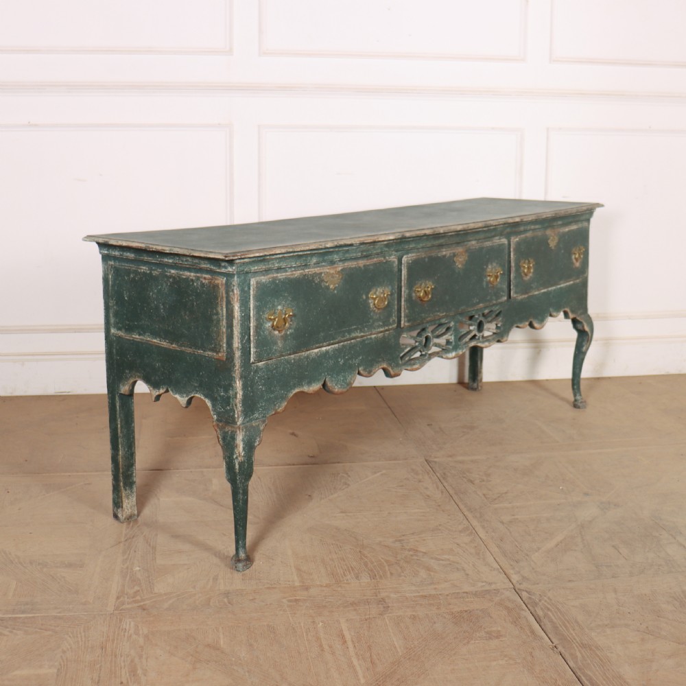 A long antique green painted dresser base featuring three drawers with brass handles, a scalloped apron with pierced fretwork, and cabriole legs. View X
