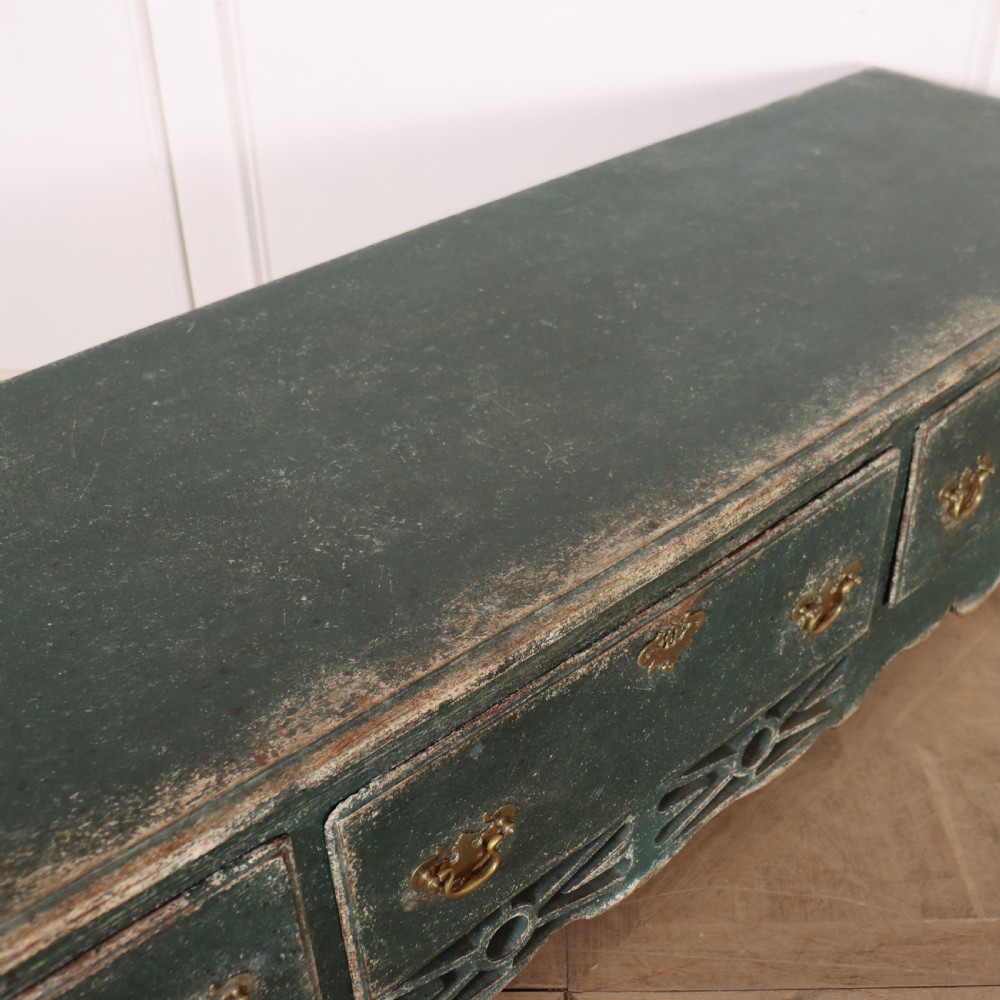 A long antique green painted dresser base featuring three drawers with brass handles, a scalloped apron with pierced fretwork, and cabriole legs. View XIII