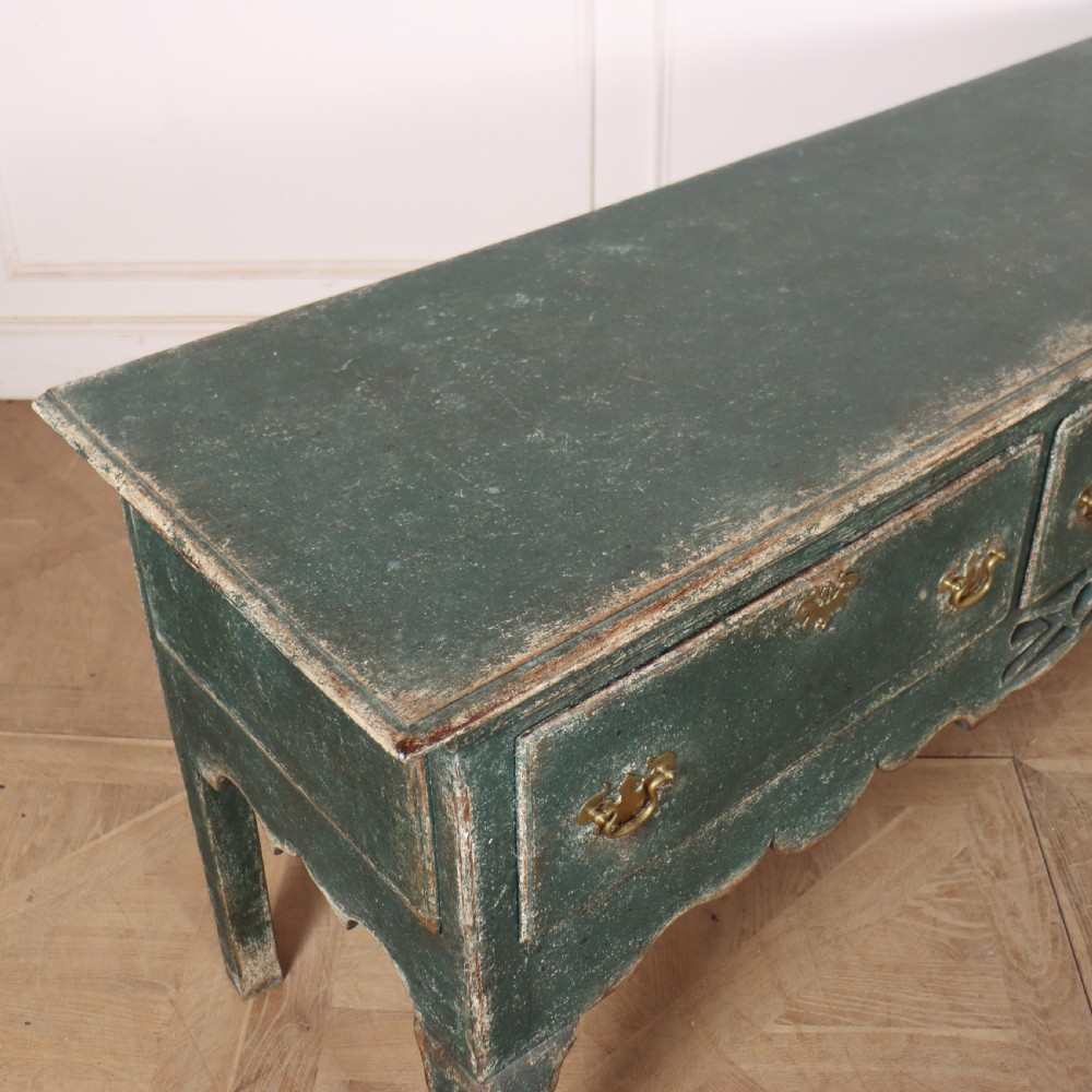 A long antique green painted dresser base featuring three drawers with brass handles, a scalloped apron with pierced fretwork, and cabriole legs. View XIV
