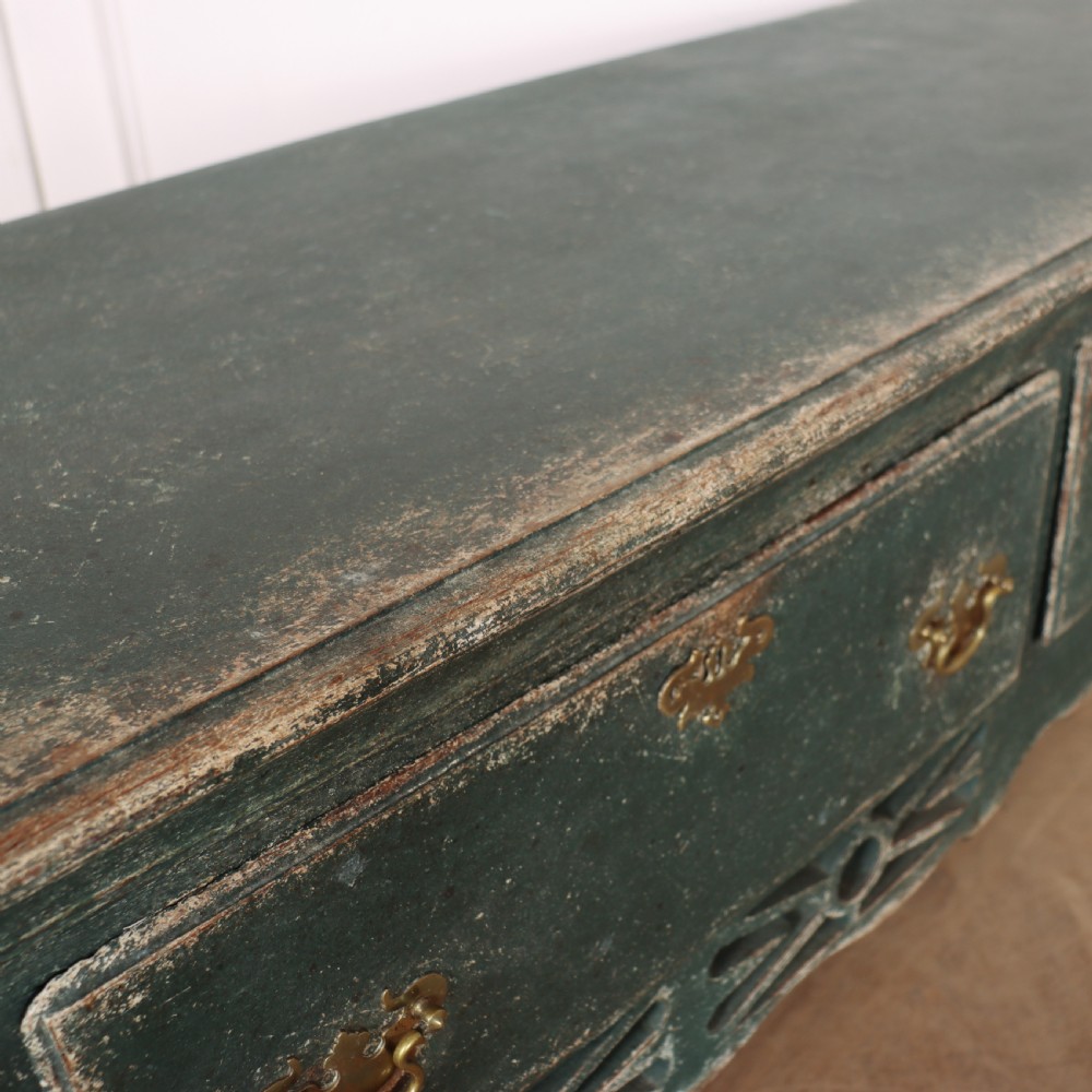 A long antique green painted dresser base featuring three drawers with brass handles, a scalloped apron with pierced fretwork, and cabriole legs. View XVI