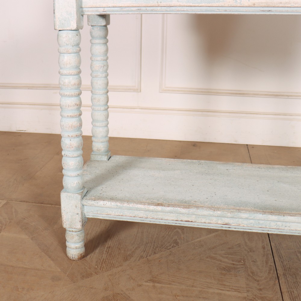 An antique painted wooden washstand featuring bobbin turned legs, a lower shelf, a pale blue distressed finish, and a white marble top with a splashback. View III
