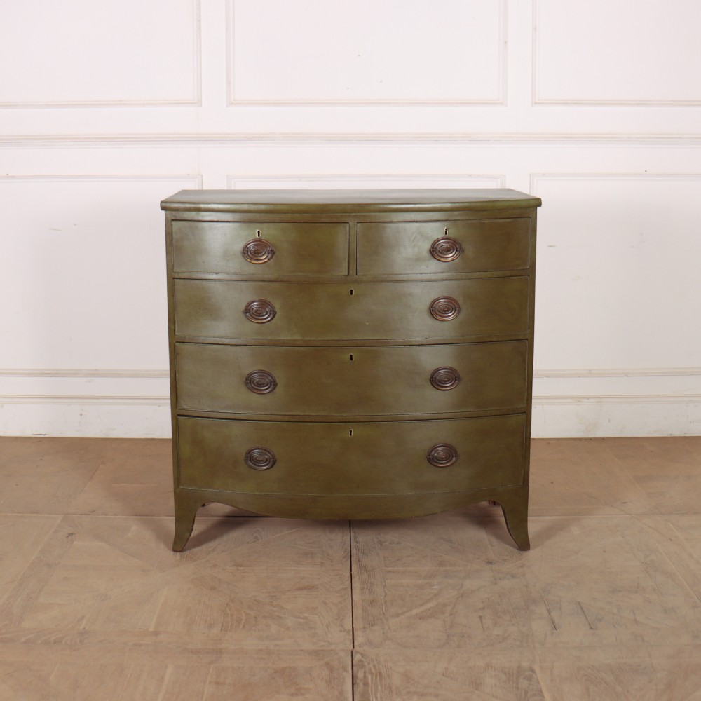 An antique olive green painted bowfront chest of drawers with two short over three long drawers and oval brass handles.
