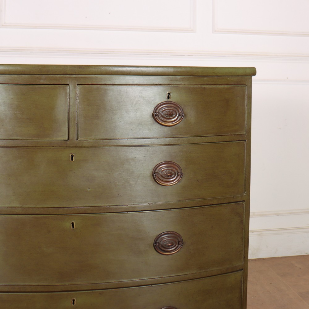 An antique olive green painted bowfront chest of drawers with two short over three long drawers and oval brass handles. View II