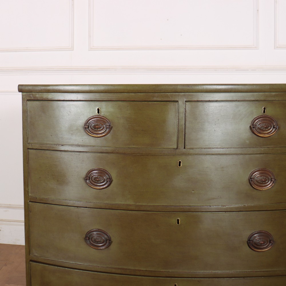 An antique olive green painted bowfront chest of drawers with two short over three long drawers and oval brass handles. View III