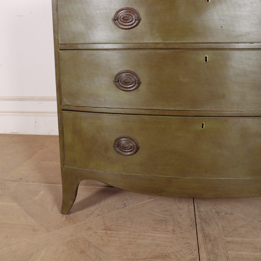 An antique olive green painted bowfront chest of drawers with two short over three long drawers and oval brass handles. View V