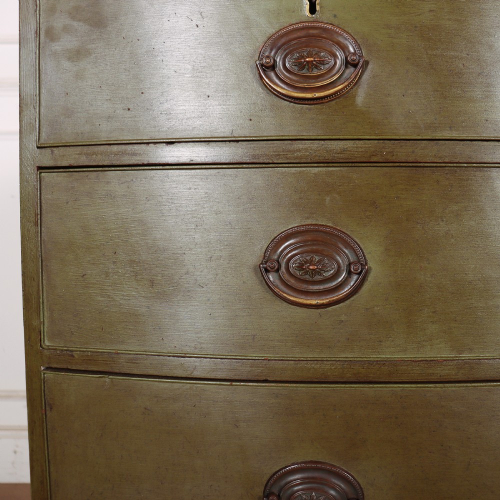 An antique olive green painted bowfront chest of drawers with two short over three long drawers and oval brass handles. View VI