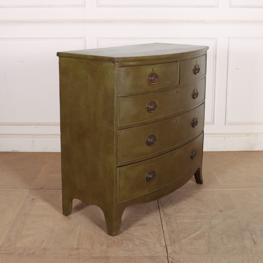 An antique olive green painted bowfront chest of drawers with two short over three long drawers and oval brass handles. View VIII