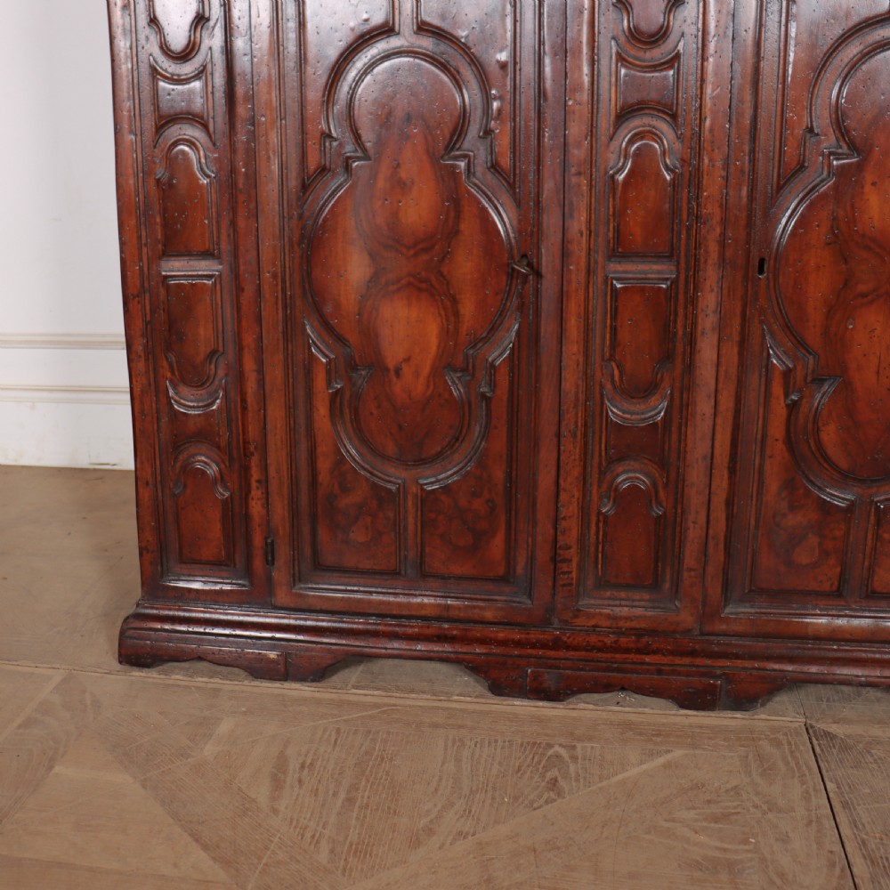 An antique dark walnut Italian sideboard featuring three upper frieze drawers and three carved panelled doors. View III