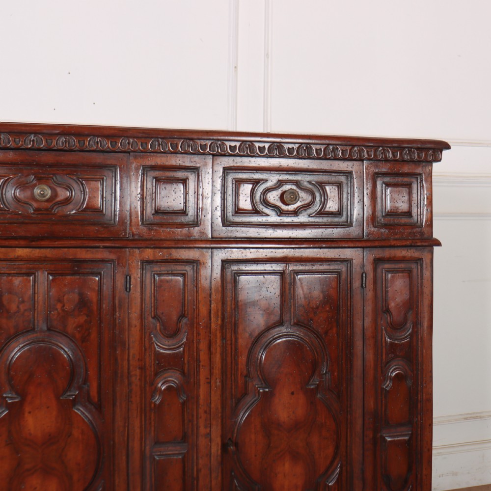 An antique dark walnut Italian sideboard featuring three upper frieze drawers and three carved panelled doors. View VI
