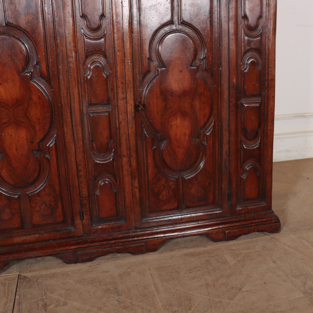 An antique dark walnut Italian sideboard featuring three upper frieze drawers and three carved panelled doors. View VII
