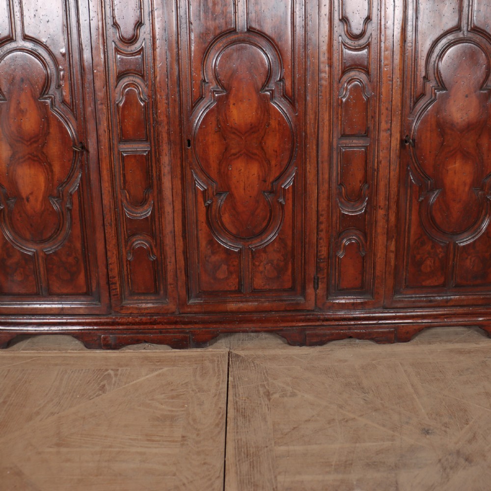 An antique dark walnut Italian sideboard featuring three upper frieze drawers and three carved panelled doors. View VIII