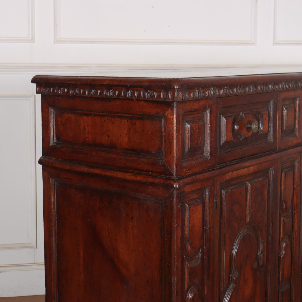 An antique dark walnut Italian sideboard featuring three upper frieze drawers and three carved panelled doors. View XII